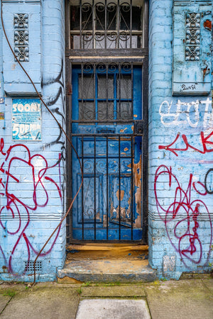 Blaue Tür und Graffiti an einer abgenutzten Fassade in East London