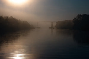 Un canal de Florida se desvanece en la cálida niebla de la mañana debajo de un puente.
