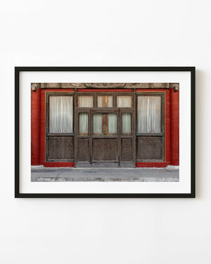 Carved wooden doors and pale curtains stand within red walls at Beijing’s Forbidden City