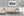 Dunkles Wasser und felsige kanadische Hügel umrahmen einen fernen Güterzug