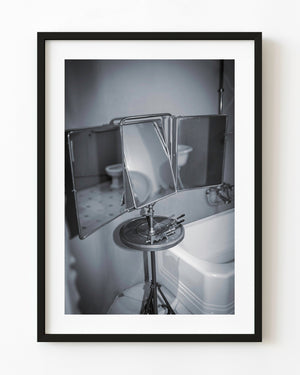Ein zusammenklappbarer Vintage-Badezimmerspiegel neben einer weißen Badewanne in einem Gaudí-Gebäude, fotografiert in Schwarzweiß