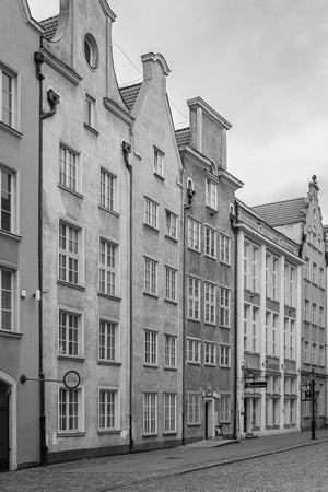 Vertical monochrome photograph of historic Gdańsk buildings with repeated white-framed windows