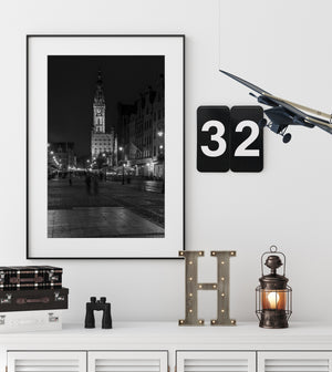 A monochrome Gdańsk night scene with the town hall tower and reflective pavement