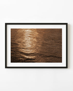 Golden sunlight shimmers across Alaskan ocean water in an abstract photograph