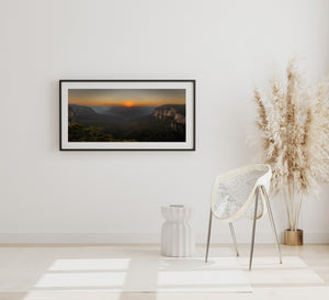 Warm orange light contrasts with shadowed cliffs and dense forest at Govetts Leap