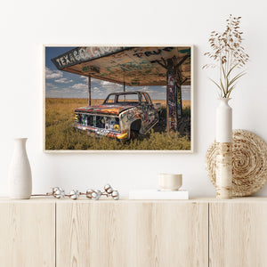 A colour photograph captures an abandoned pickup beneath a painted Texaco canopy