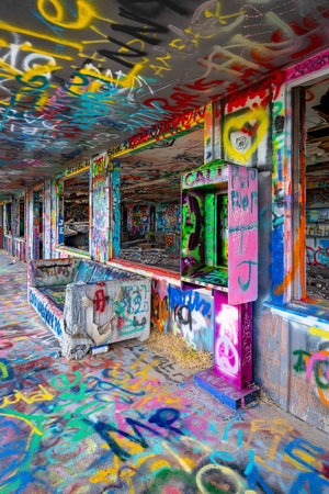 Pink and green paint covers a vacant phone box beside a graffiti-covered couch