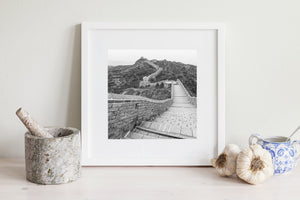 Ein quadratisches Schwarzweißfoto folgt dem gewundenen Steinweg der Chinesischen Mauer.