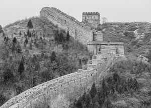 Steep brick battlements climb toward a Great Wall watchtower among bare trees