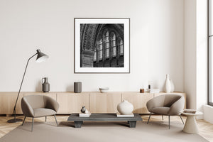 Light shines through tall patterned windows beneath a sweeping masonry arch