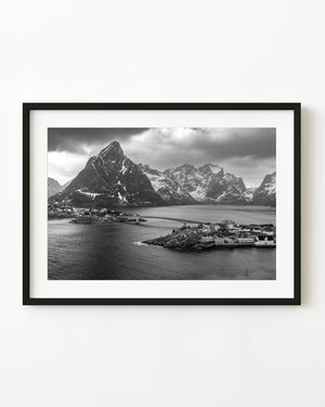 Un puente une las casas frente al mar de Hamnøy debajo de las montañas nevadas de Lofoten en blanco y negro