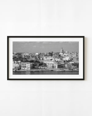 Havana skyline across harbour water with El Capitolio rising above the rooftops in black and white.