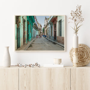 Havana street scene with people beneath balconies and overhead wires between worn colourful facades.