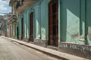 Colour street photograph of turquoise walls, ornate iron grilles and painted Fidel lettering in Havana.