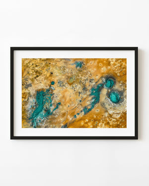 Aerial view of turquoise geothermal pools scattered across orange and pale mineral-stained ground in Iceland.