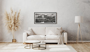 Schwarz-Weiß-Fotografie von Islands felsiger Landschaft, schneebedeckten Gipfeln und flachem Vordergrundwasser.