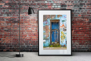 London street detail with a blue wooden door, rusted gate and painted brick