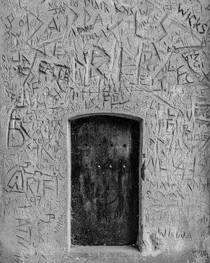 Eingelassene Holztür mit zerkratztem Graffiti in historischem Londoner Gebäude
