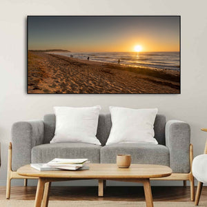 Warm sunrise lights rippled beach sand and distant walkers at Long Reef