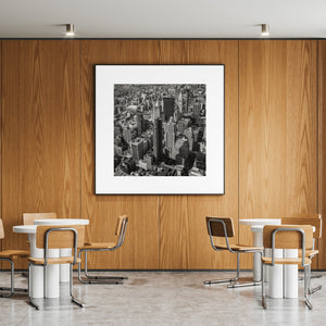 Square black and white photograph of Manhattan towers, rooftop details and city streets