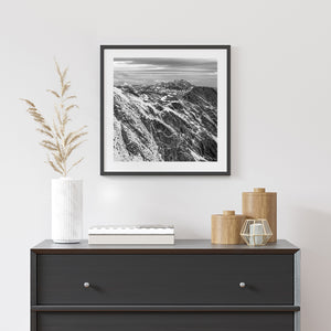 Martial Mountains snowfields contrast with dark rock beneath bands of cloud