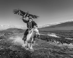 Foto in bianco e nero del cavaliere kazako dell'aquila che attraversa l'acqua a cavallo