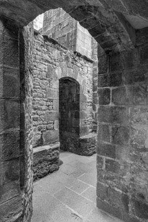 A broad stone arch frames a narrow doorway in a textured medieval wall