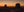 Two sandstone formations rise above a shadowed desert floor