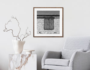 Rustikale Scheunenwand aus Stein und Fensterläden aus dunklem Holz in Schwarzweiß