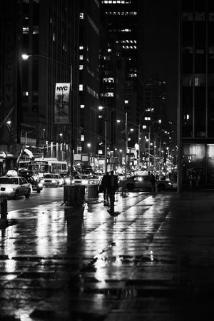 Street lights reflecting across a wet Manhattan sidewalk