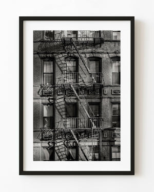 Black and white New York City brick facade with fire escapes