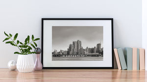 Vista en blanco y negro de las torres de Manhattan tras un muelle bajo junto al río