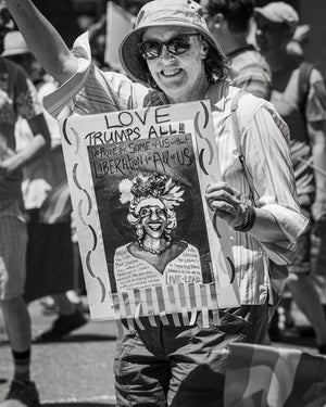 Street portrait of a smiling marcher wearing sunglasses and a sun hat