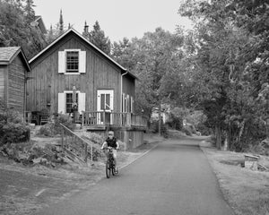 Photographie en noir et blanc d'un garçon faisant du vélo le long d'une voie tranquille de l'Ontario