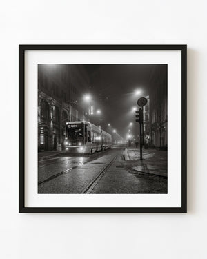 Oslo tram in dense night fog beneath glowing street lamps, black and white