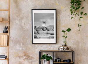 Photographie de phare en noir et blanc avec rochers côtiers texturés