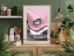 Round vintage headlight set into the pink bodywork of a classic Oldsmobile