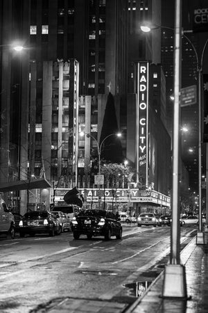 Photographie nocturne en noir et blanc du Radio City Music Hall et de la Sixième Avenue