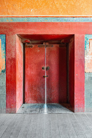 Puertas de madera rojas debajo de yeso naranja y adornos decorativos turquesa en Beijing