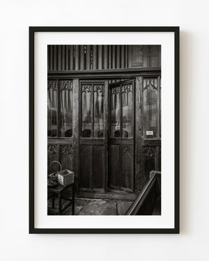 Carved church door beneath organ pipes in Rye in black and white