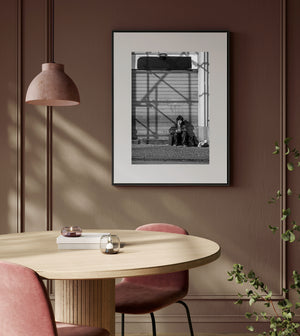 Black and white street portrait with a woman seated against a shutter