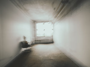 Soft blurred room with a dark chair beside a sunlit window