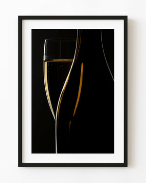 Sparkling wine flute and dark bottle outlined by golden light against black.