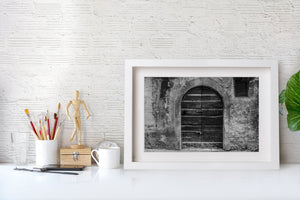 Puerta arqueada con candado en una fachada desgastada de Spoleto.