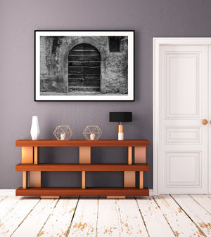 Puerta histórica de Spoleto con madera desgastada y piedra tosca en monocromo.