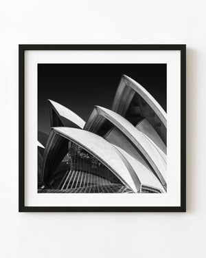 Sydney Opera House shells rise against a dark sky in black and white.