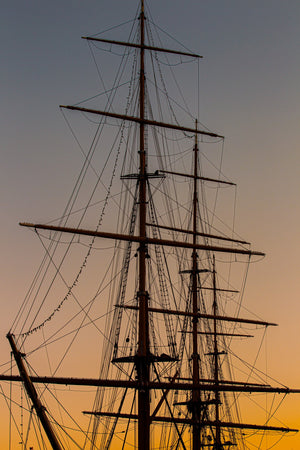 Dark spars and rope ladders cross a softly glowing orange and grey sky.