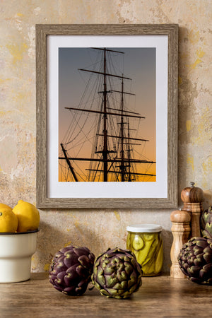 Tall ship spars, ropes and climbing ladders silhouetted against a golden horizon.