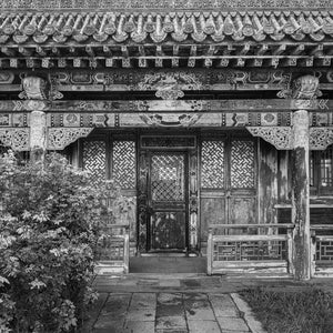 Decorative temple doorway framed by carved beams, lattice windows and weathered columns.