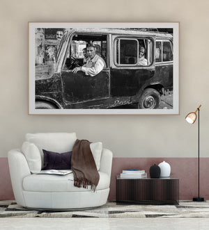 Three men in a battered Mysore truck beside a wall of street posters.